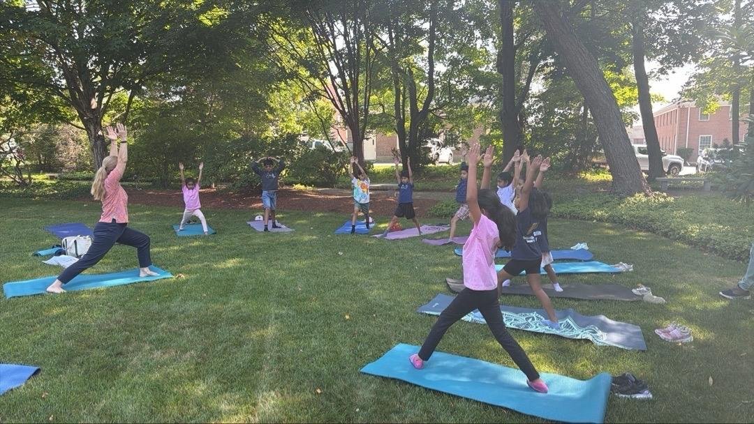 Kids doing yoga on colorful mats on the grass